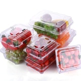 A stack of fruit and vegetables in plastic clamshell containers on a white background