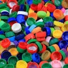 Close-up of a pile of plastic bottle caps in red, green, yellow, orange, and blue