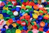 Close-up of a pile of plastic bottle caps in red, green, yellow, orange, and blue