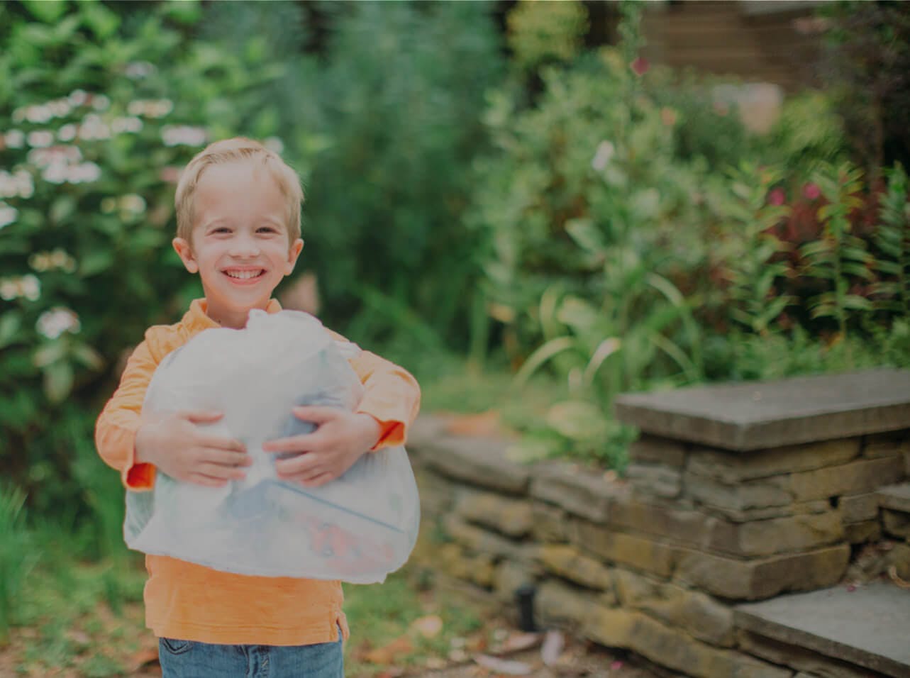 Smiling child holding Ridwell bag