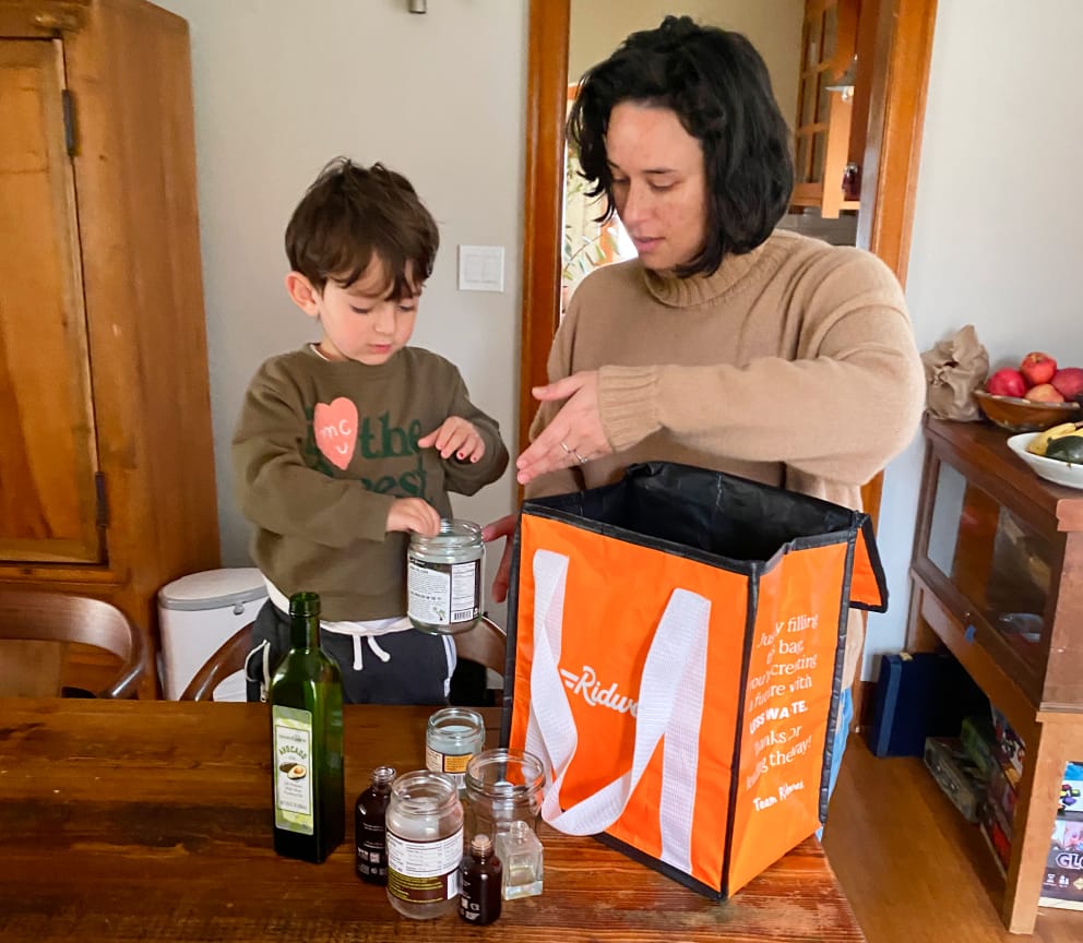 Ridwell Co-Founder Aliya Marder shows a child how to recycle glass bottles and jars from home